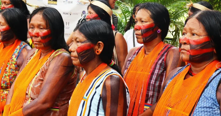 Indigenous women with painted faces and orange scarves