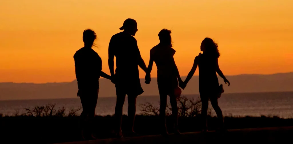 a silhouette of a family of four against a sunset sky