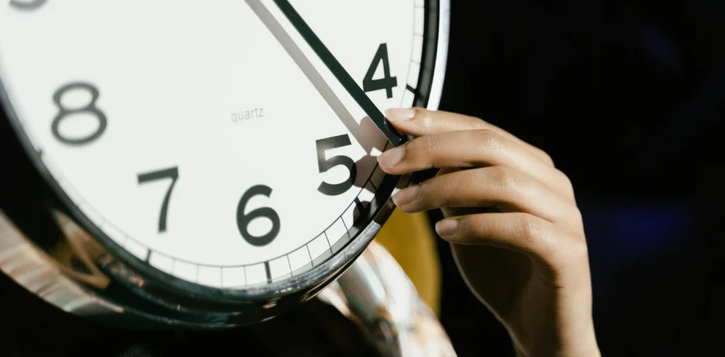 a close up of a clock face with a human hand holding one of the clock hands