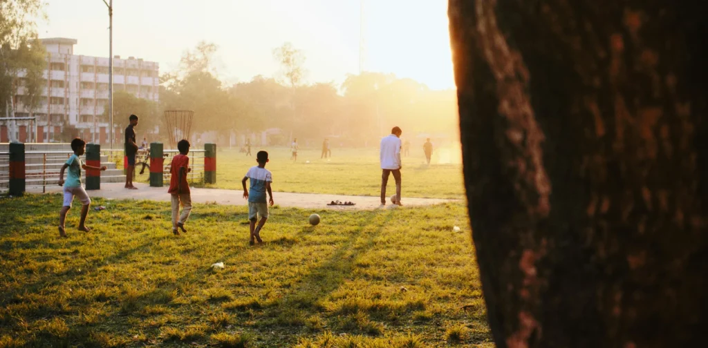 children playing football at a park on grassy field