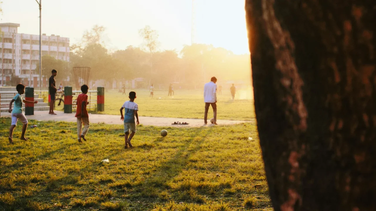 children playing football at a park on grassy field