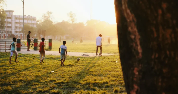children playing football at a park on grassy field