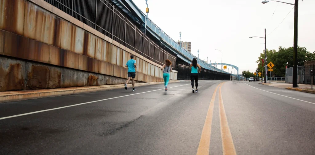 Long shot of people jogging along a wide city street free of cars