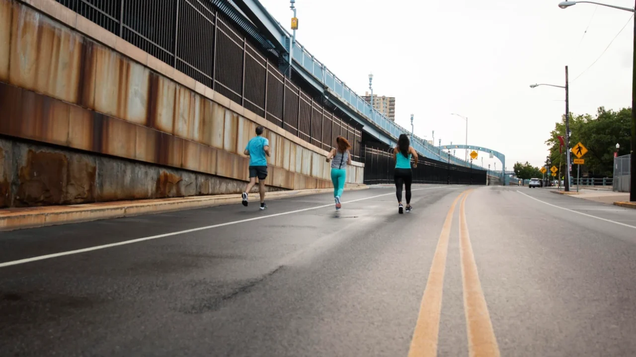 Long shot of people jogging along a wide city street free of cars