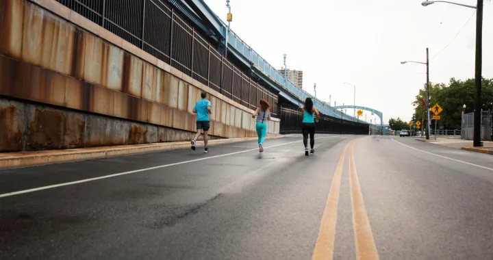 Long shot of people jogging along a wide city street free of cars
