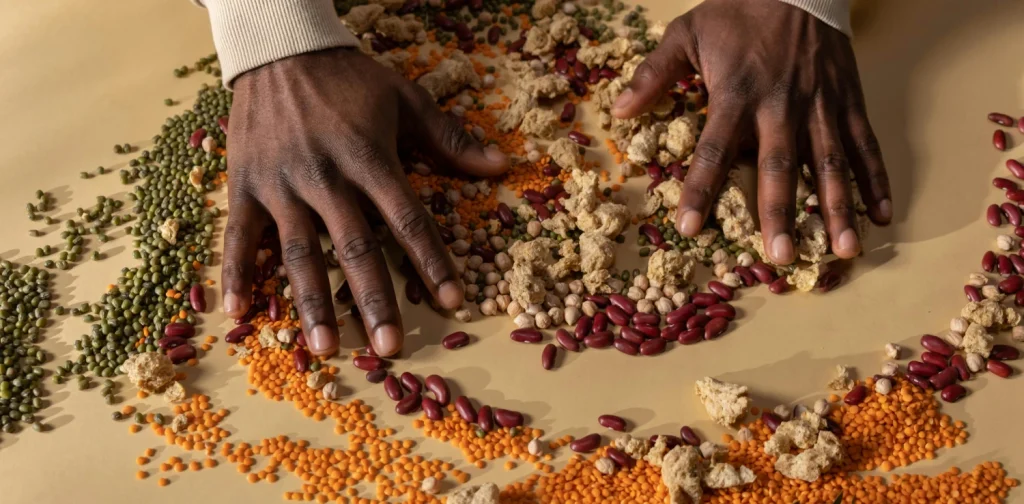 two hands mixing various beans and grains on a table