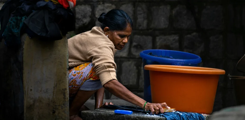 A woman crouching down to wash clothes