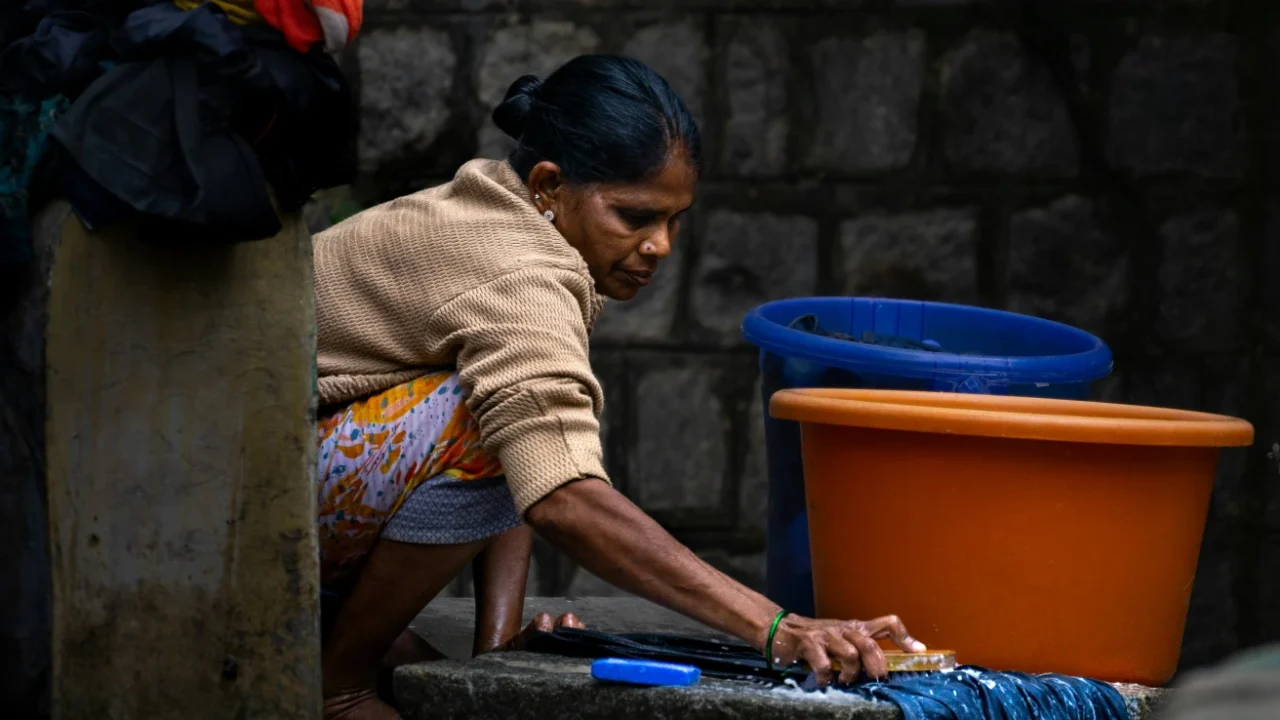 A woman crouching down to wash clothes