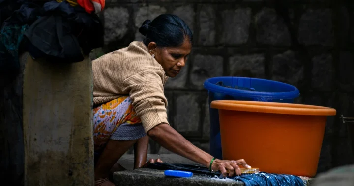 A woman crouching down to wash clothes