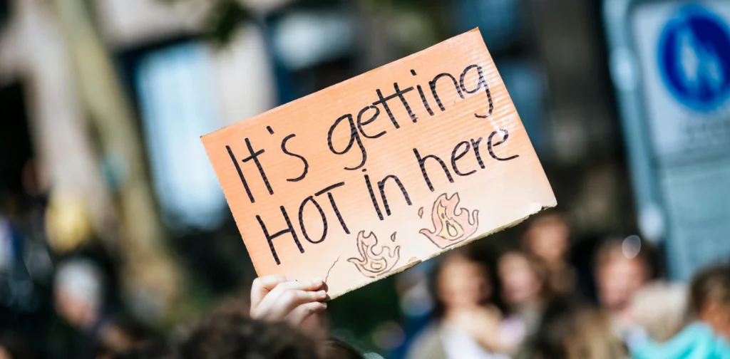 a hand holding a sign that says ‘it’s getting hot in here’