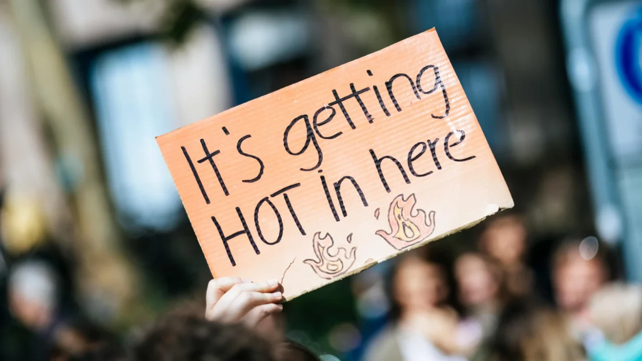 a hand holding a sign that says ‘it’s getting hot in here’