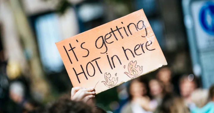 a hand holding a sign that says ‘it’s getting hot in here’