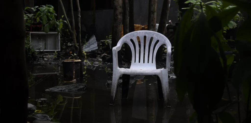 a white plastic chair in a flooded garden