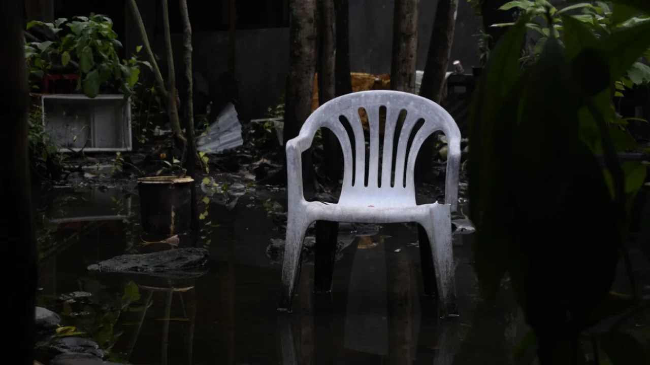a white plastic chair in a flooded garden