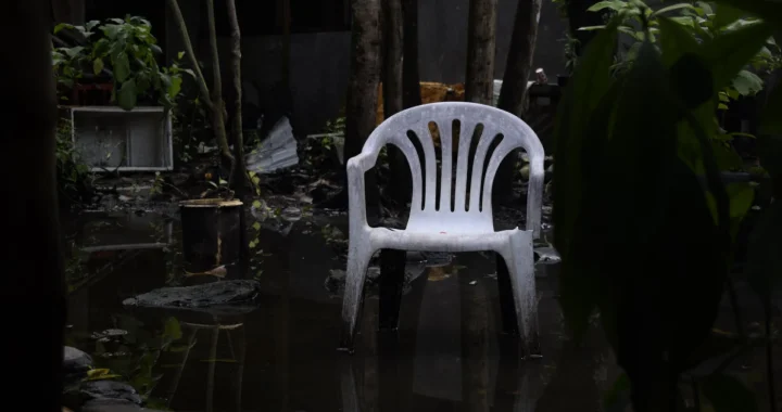 a white plastic chair in a flooded garden