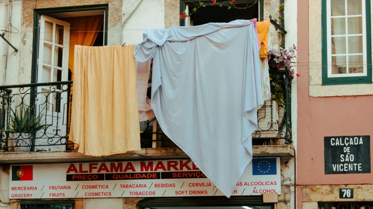 laundered sheets hanging from the window on the second floor of a local market store in alfama, lisbon