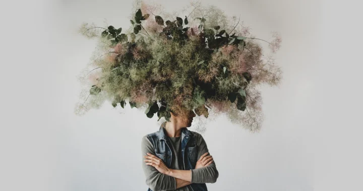 Large decorative bouquet made of green leaves and moss hangs over man's head