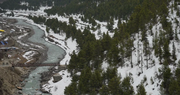 snow covered alley in the himalaya, a river stream, and a bridge going across the river
